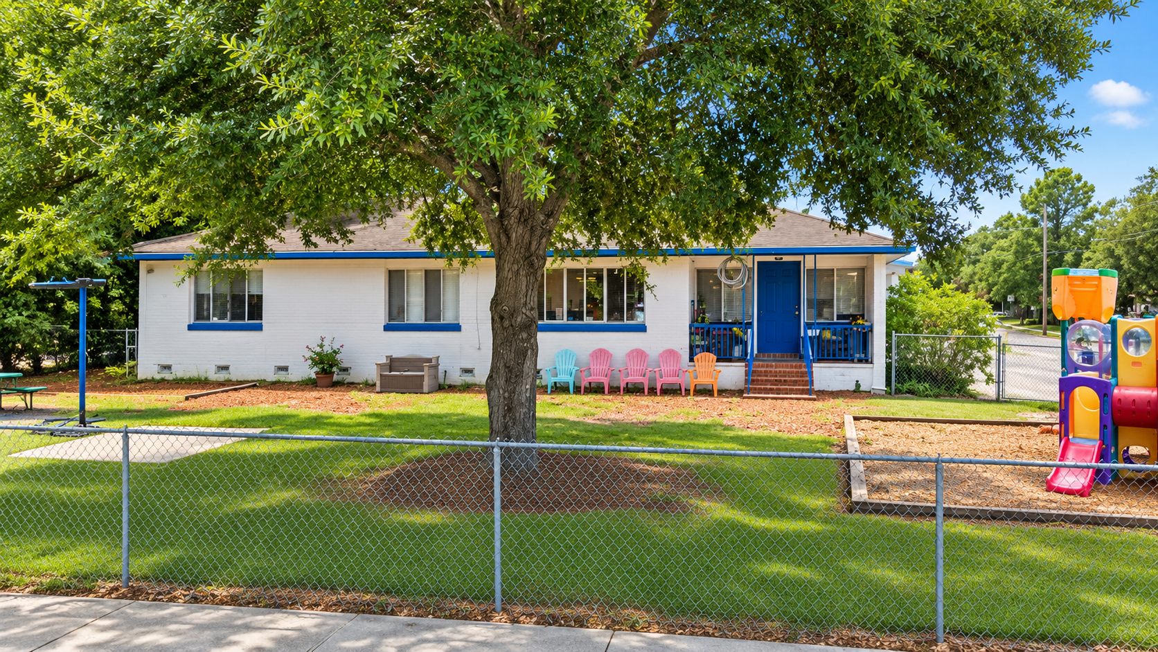 The existing preschool building and play yard under oak trees before redevelopment