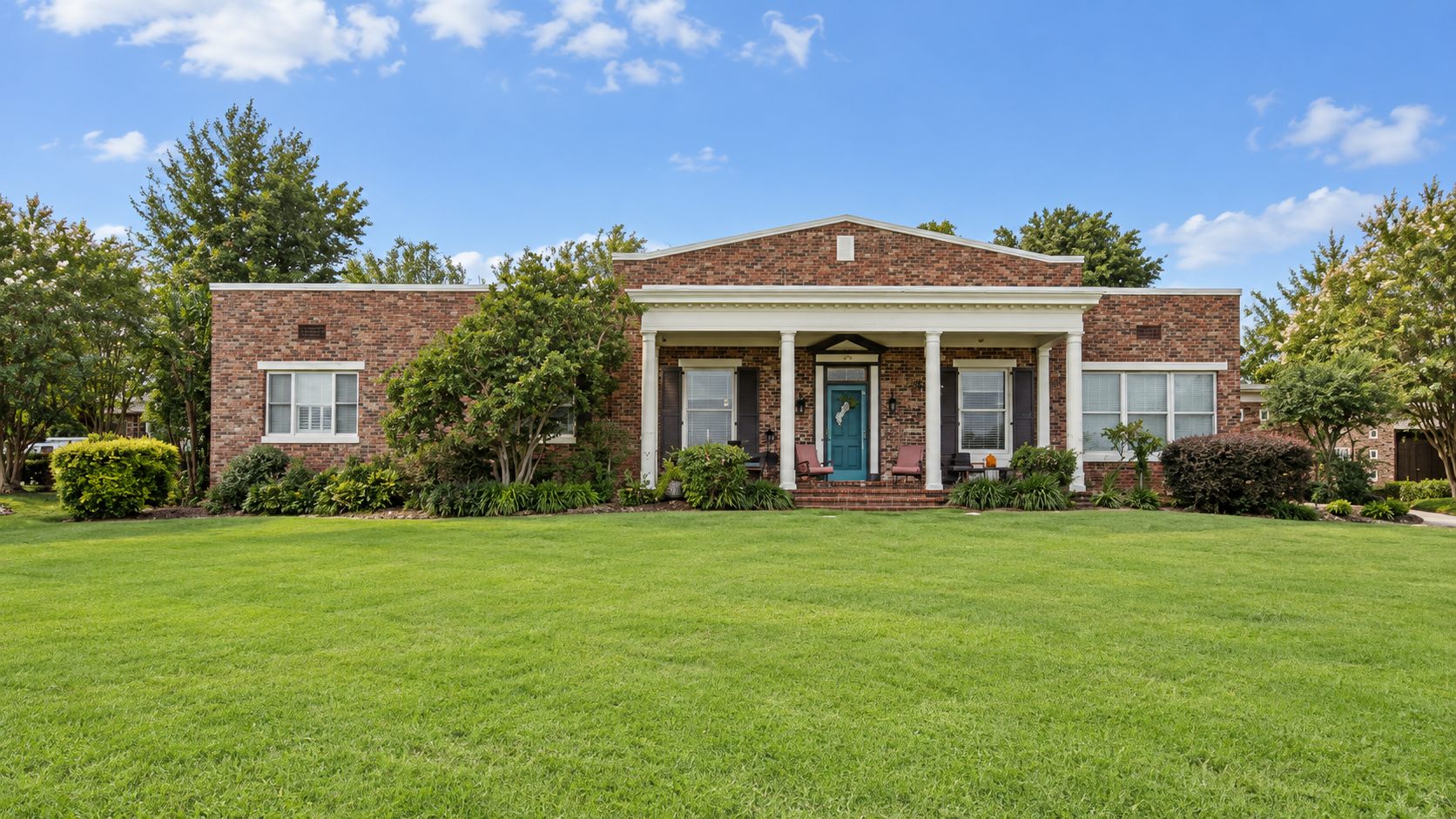 The existing Hammen home before the addition: a brick house with a white columned portico and teal front door