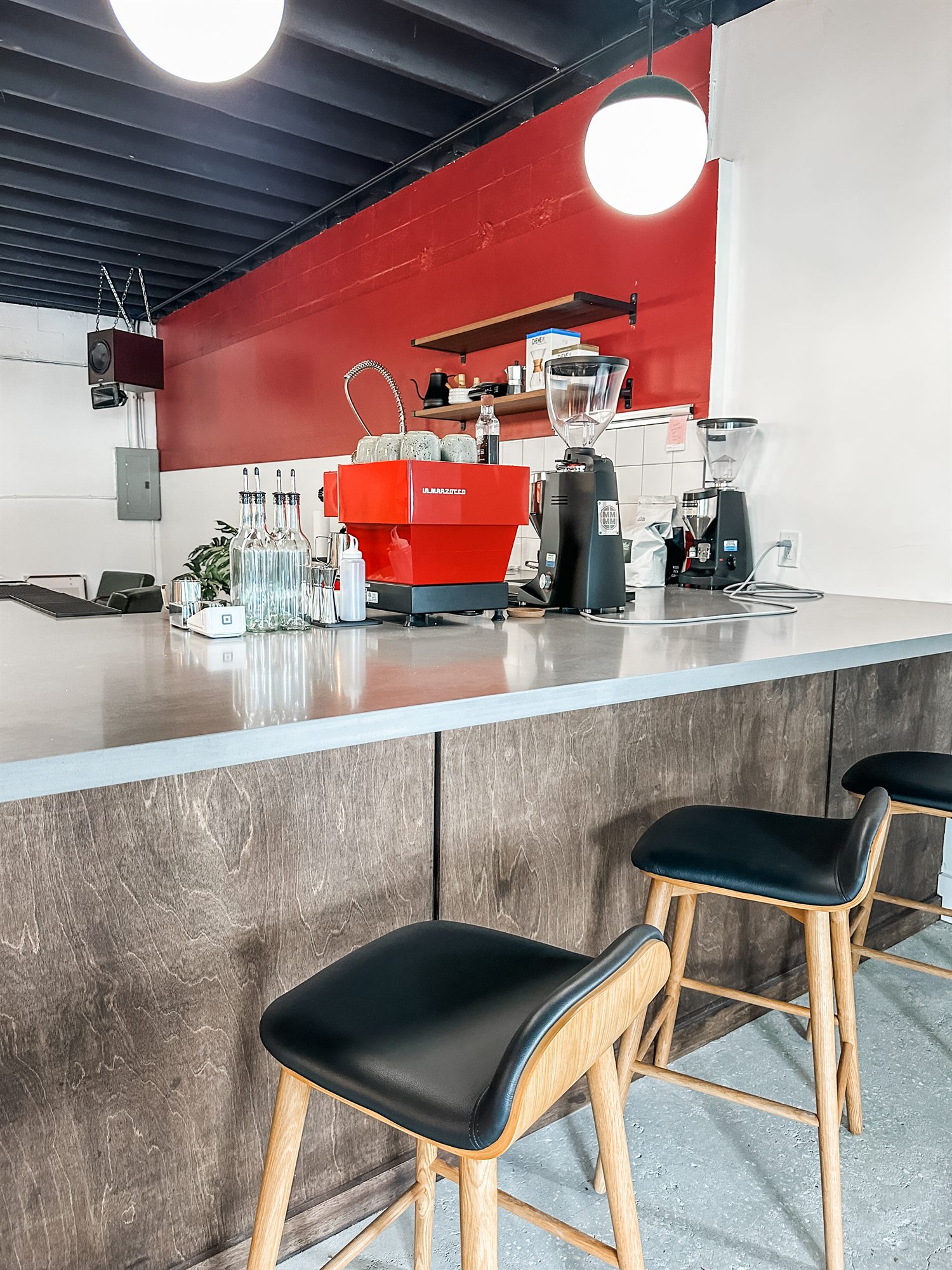 Bar stools along the customer counter beneath the red accent wall