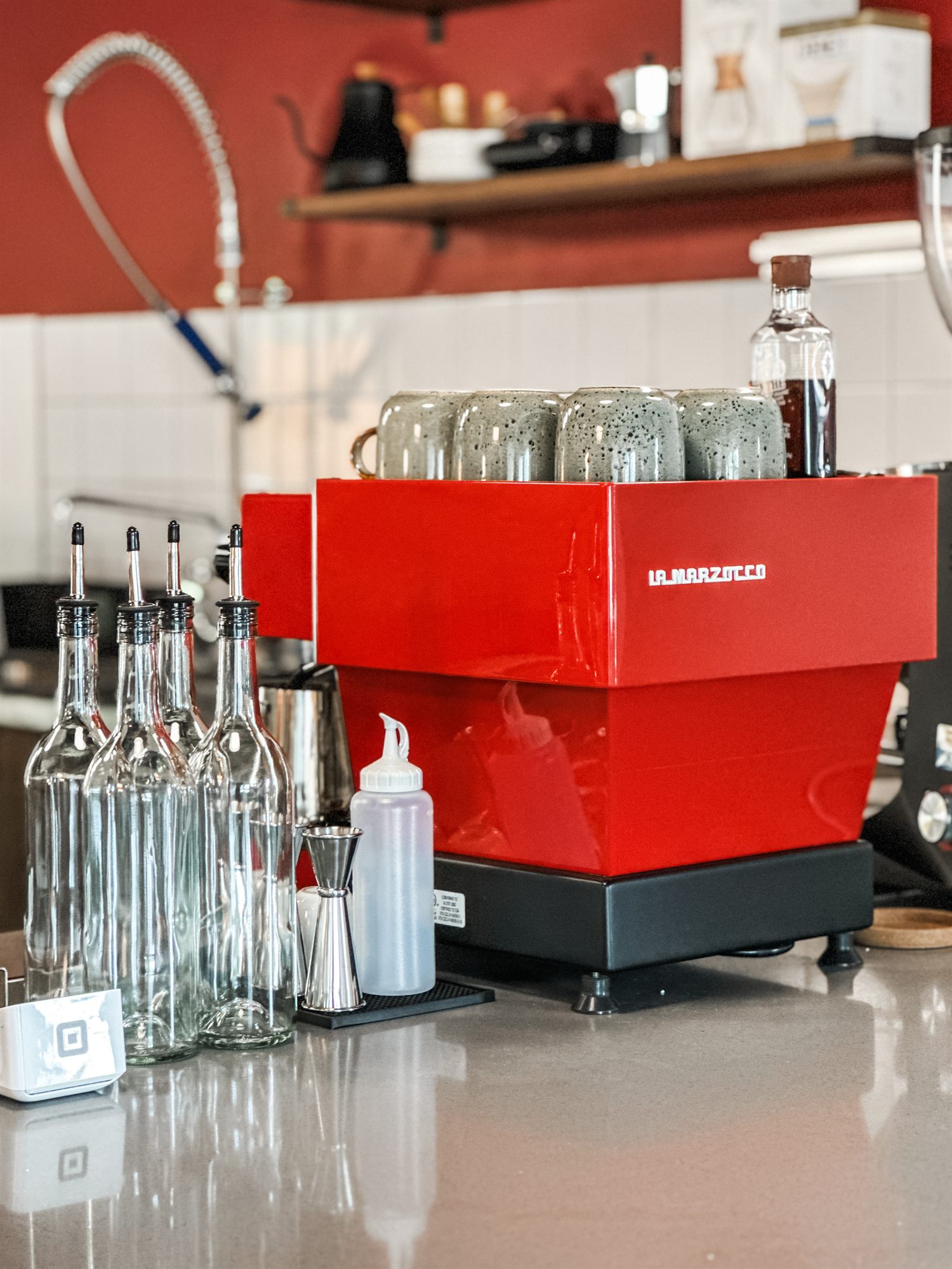 Red espresso machine and bottles on the counter