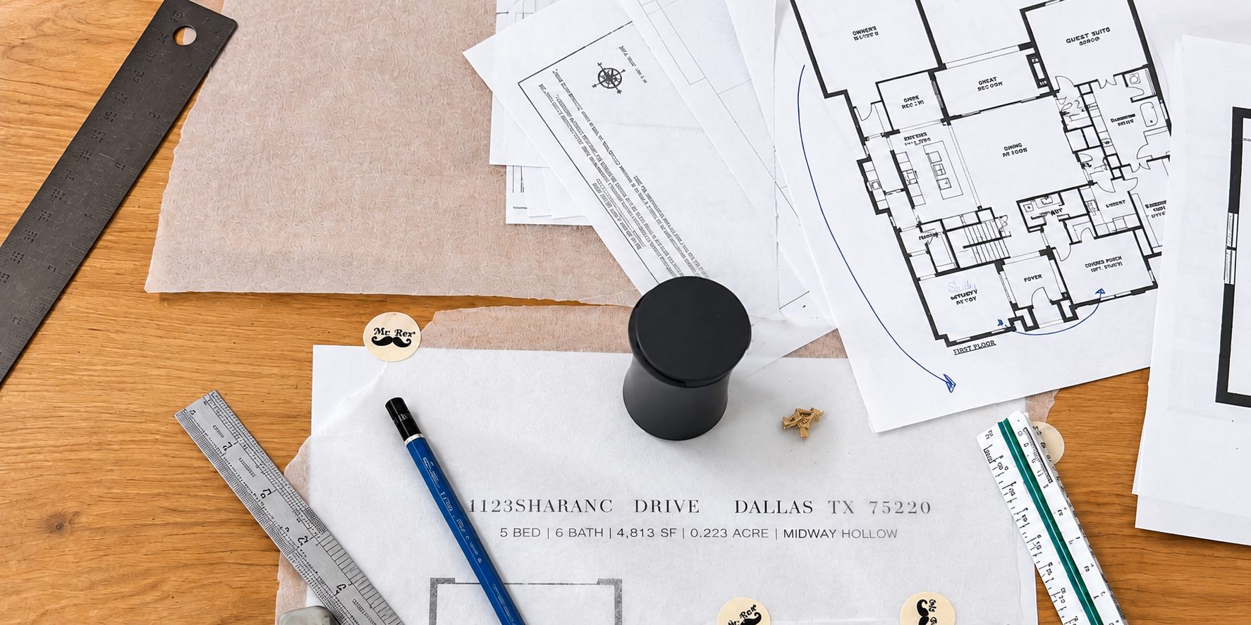 Floor plans, tracing paper, and drafting tools on a studio desk